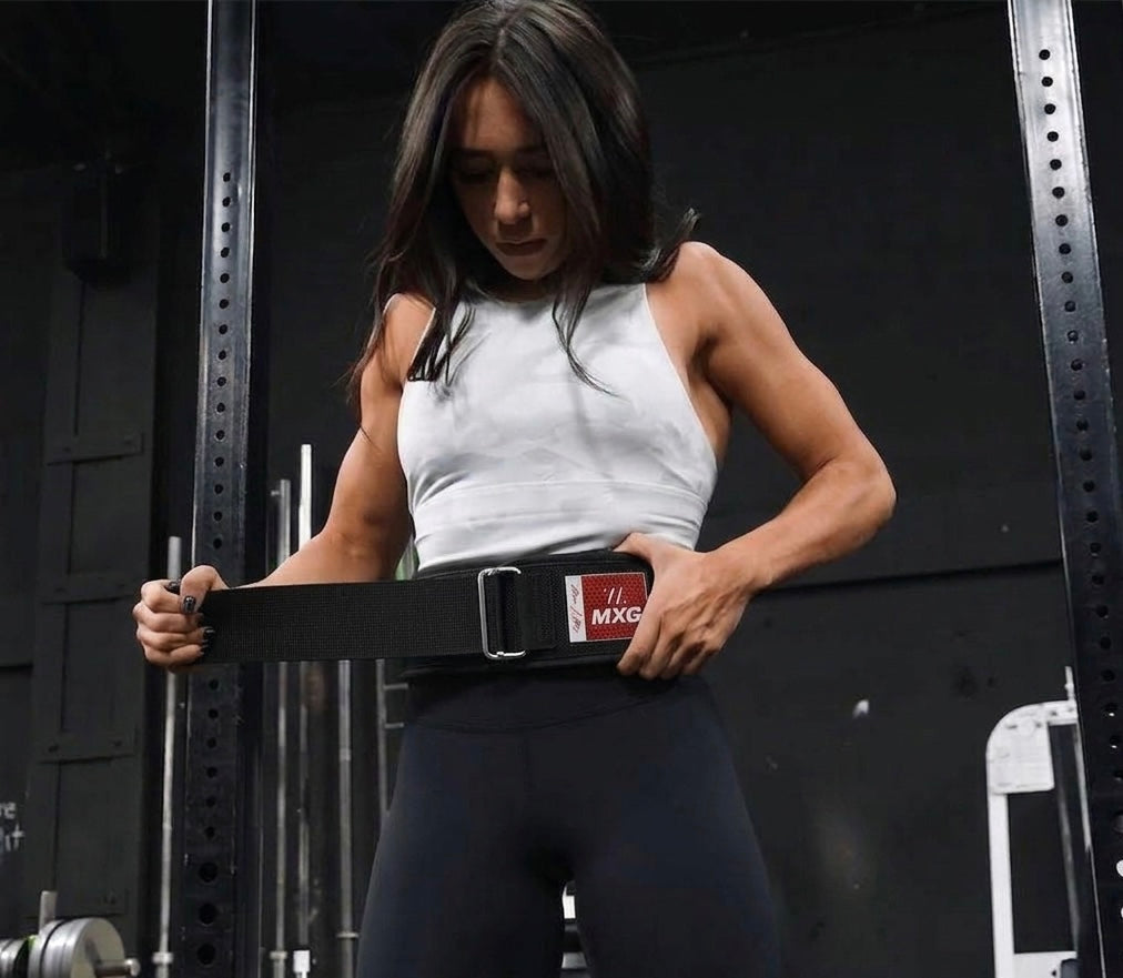 Female athlete adjusting an MXG weightlifting belt before a strength training workout in the gym