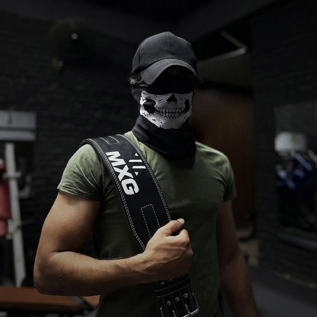 Man wearing a black skull face mask and green t-shirt with a weightlifting belt strapped over his shoulder in a gym