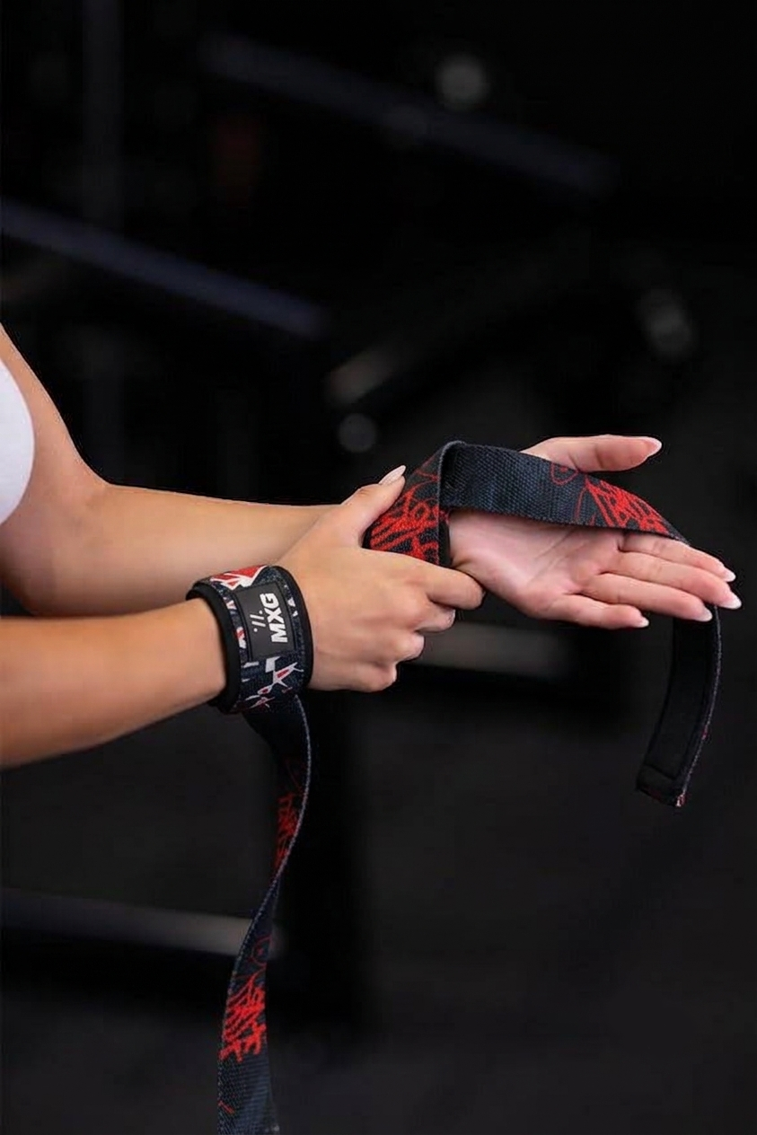 Woman putting on black and red MXG lifting straps, wrist loop on one hand and strap over the other palm